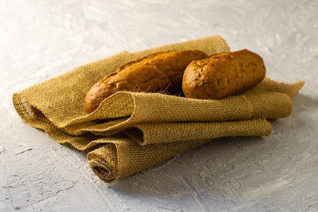 two fresh rye buns on burlap on a gray background. High quality photo