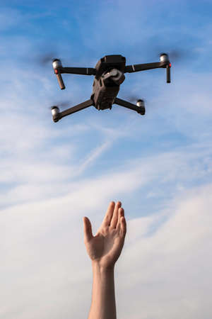 a tourist guy launches a quadrocopter and reaches for it with his hand. High quality photoの写真素材