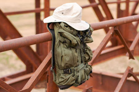 a tourist's backpack and hat hang on the railing of the old iron bridge over the river concept of travel tourism. High quality photoの写真素材