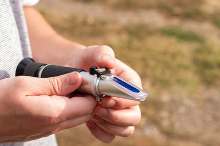 the grower holds a refractometer in his hands to determine the amount of sugar in grape juice. High...