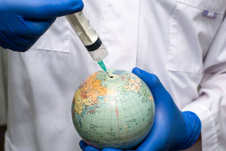 the doctor pricks the globe with a syringe concept vaccination. High quality photoの写真素材