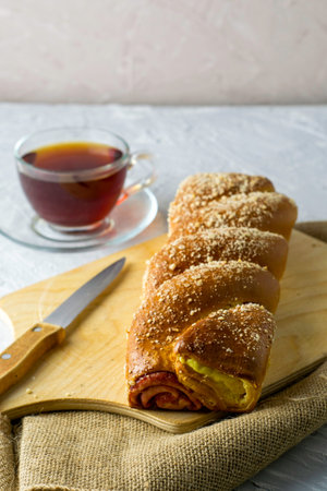 cherry-vanilla strudel knife and a cup of tea on a light gray surface. High quality photo