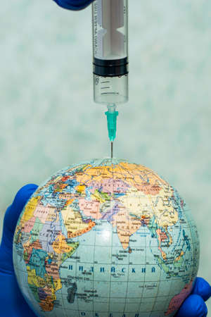 the doctor pricks the globe with a syringe concept vaccination. High quality photoの写真素材