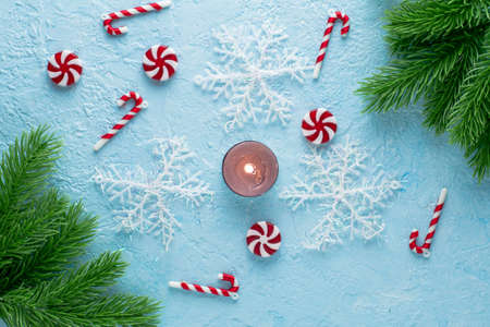 new Year's Christmas background on a blue surface fir twigs snowflakes candies and a burning candle. High quality photoの写真素材