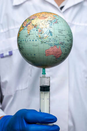 the doctor pricks the globe with a syringe concept vaccination. High quality photoの写真素材
