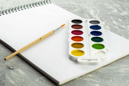 watercolor paints brush and sketchbook for drawing on a gray-white surface. High quality photoの写真素材