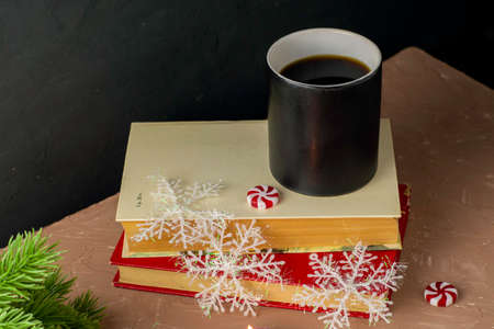 christmas card a cup of coffee on books christmas candies snowflakes and fir twigs. High quality photoの写真素材