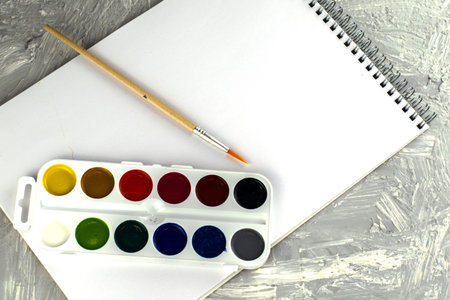 watercolor paints brush and sketchbook for drawing on a gray-white surface. High quality photoの写真素材