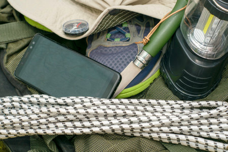backpack sneakers hat compass rope folding knife tent lantern and smartphone with open map travel...