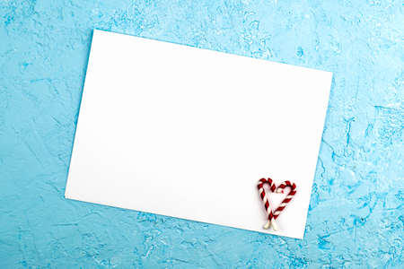 a white sheet on a blue surface in the lower corner of the sheet are Christmas candies folded with a heart a conceptual letter to Santa Claus with New Year's wishes. High quality photoの写真素材