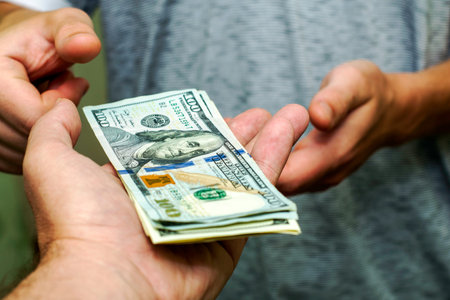 one person passes another a bundle of hundred dollar bills counting them. High quality photoの写真素材