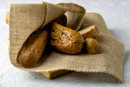 two fresh rye buns on burlap one of the buns is cut next to a knife. High quality photoの写真素材