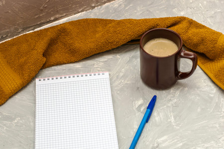a cup of cappuccino coffee a notepad and a fountain pen on a gray surface. High quality photo