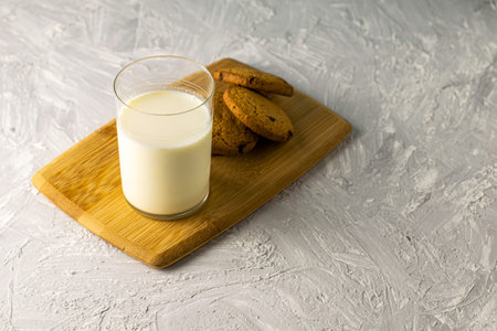oatmeal cookies and a glass of milk on a wooden cutting board on the table. High quality photoの写真素材