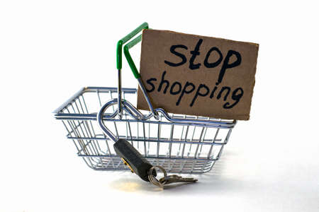 the concept of refusing to buy reasonable consumption is a shopping basket with a padlock and a sign saying stop shopping on a white backgroundの写真素材