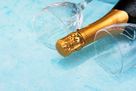 a bottle of champagne and two glass glasses lying on a blue background close-up. High quality photo