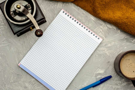 a cup of coffee cappuccino coffee grinder notepad and fountain pen on a gray surface. High quality photoの写真素材