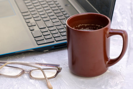 a cup of latte coffee and glasses next to a laptop. High quality photoの写真素材