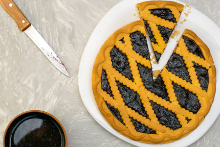 a shortbread pie with blueberries on a white plate with a cut piece, a knife and a mug of tea on the table. High quality photoの写真素材