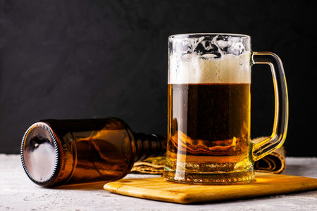 a glass of beer, an empty beer bottle, a cork and dried fish on burlapの写真素材