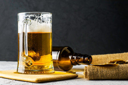 a glass of beer, an empty beer bottle, a cork and dried fish on burlap. High quality photo
