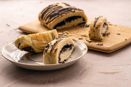sliced puff pastry bun with poppy seeds and chocolate on a cutting board and on a plate. High quality photoの写真素材