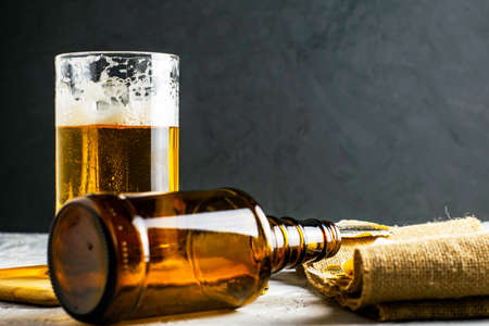 a glass of beer, an empty beer bottle, a cork and dried fish on burlap. High quality photoの写真素材