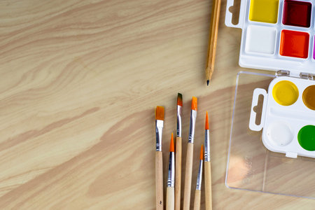watercolor paints brushes and pencil on a wooden table. High quality photoの写真素材