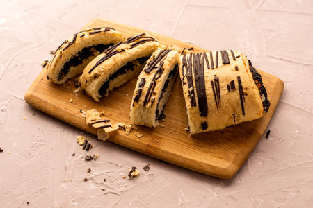 puff pastry bun with poppy seeds and chocolate cut on a cutting board. High quality photo