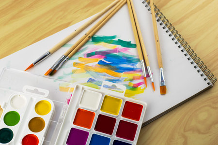 watercolor paints and brushes on a white sheet with color samples. High quality photo
