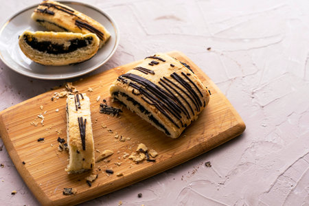 sliced puff pastry bun with poppy seeds and chocolate on a cutting board and on a plate. High...
