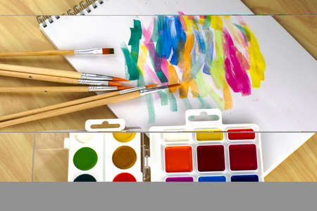 watercolor paints and brushes on a white sheet with color samples. High quality photo