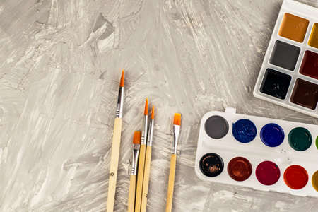 watercolor paints and brushes for drawing on a gray textured surface. high quality photoの写真素材