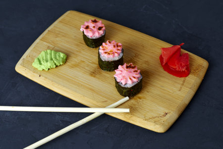 sushi and rolls on a wooden board with wasabi sticks and ginger