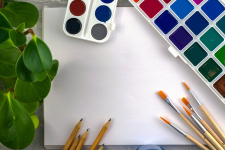 watercolor paints brushes pencils houseplant on the background of a white sheet of drawing paper....