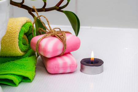 a stack of towels soap tied with string a fragrant candle and a houseplant on a table in the...