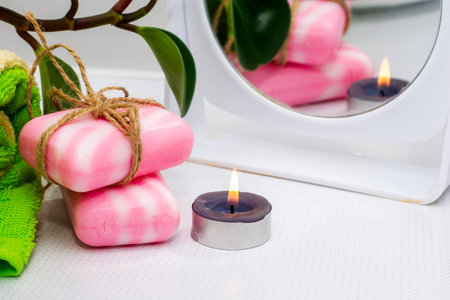 a stack of towels soap tied with string a fragrant candle a mirror and a houseplant on the bathroom table. high quality photoの写真素材