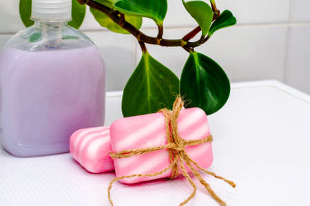 liquid soap in a bottle pieces of soap tied with string and a houseplant on a table in the bathroom. high quality photoの写真素材