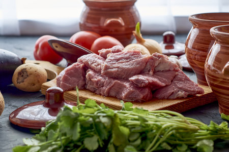 pots for cooking chanakhi and ingredients meat tomatoes potatoes garlic eggplant on the table. high...
