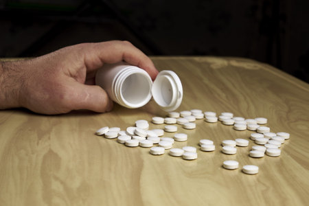 a man pours pills out of a plastic bottle on the table. high quality photo