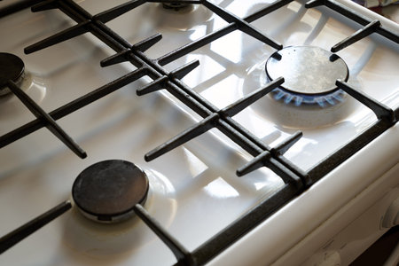 a burning gas stove on a white kitchen stove