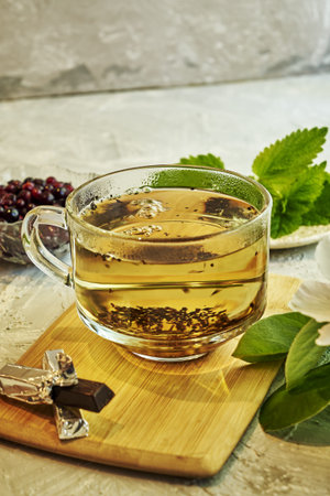 a cup of tea on the table next to chocolate mint a flowering sprig of quince and black currant in a cup. high quality photoの写真素材