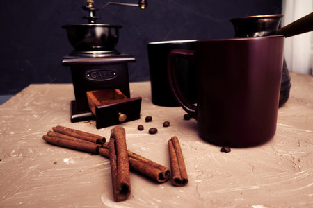 coffee grinder two mugs of cinnamon coffee beans and a turk for brewing coffee on the table. high quality photoの写真素材