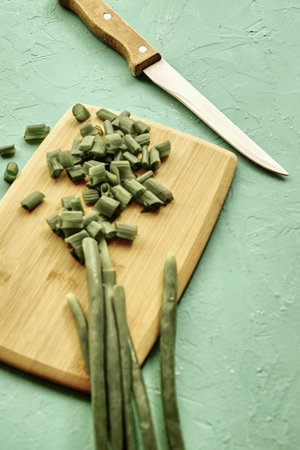 sliced green onions on a wooden chopping board next to a knife. high quality photo