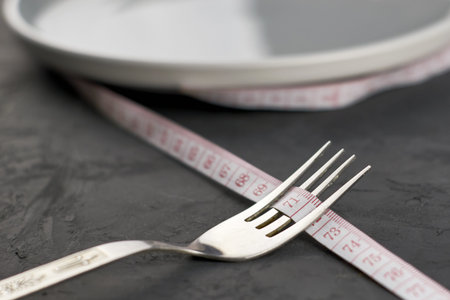 a plate wrapped with a centimeter and a fork on a black background with a copy space concept diet...
