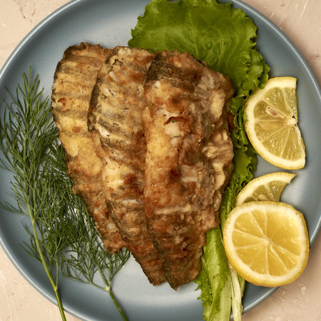 fried fish with lemon and herbs on a plate on the table top view. high quality photo