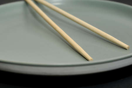 gray plate and chopsticks on a black background. high quality photoの写真素材