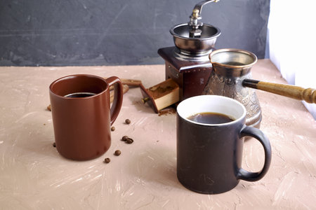 coffee grinder two mugs of cinnamon coffee beans and a turk for brewing coffee on the table. high...