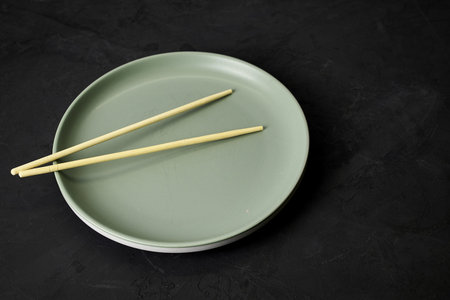 gray plate and chopsticks on a black background. high quality photo