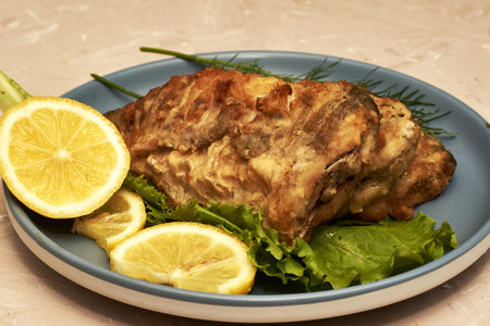 fried fish with lemon and herbs on a plate on the table. high quality photo
